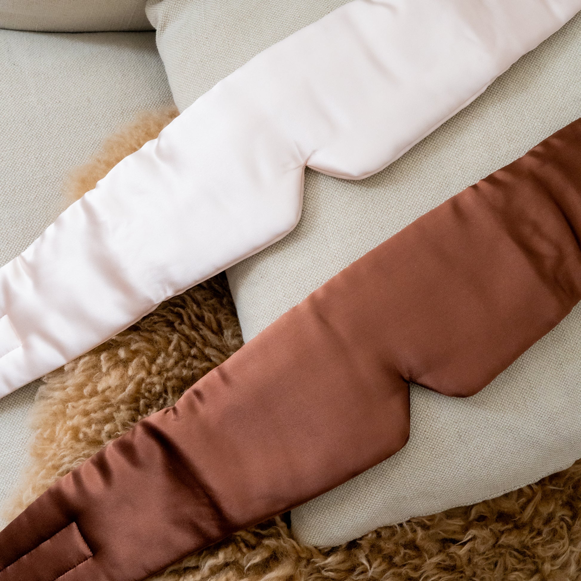 Close-up of brown, beige, and white silk eye mask on a textured surface